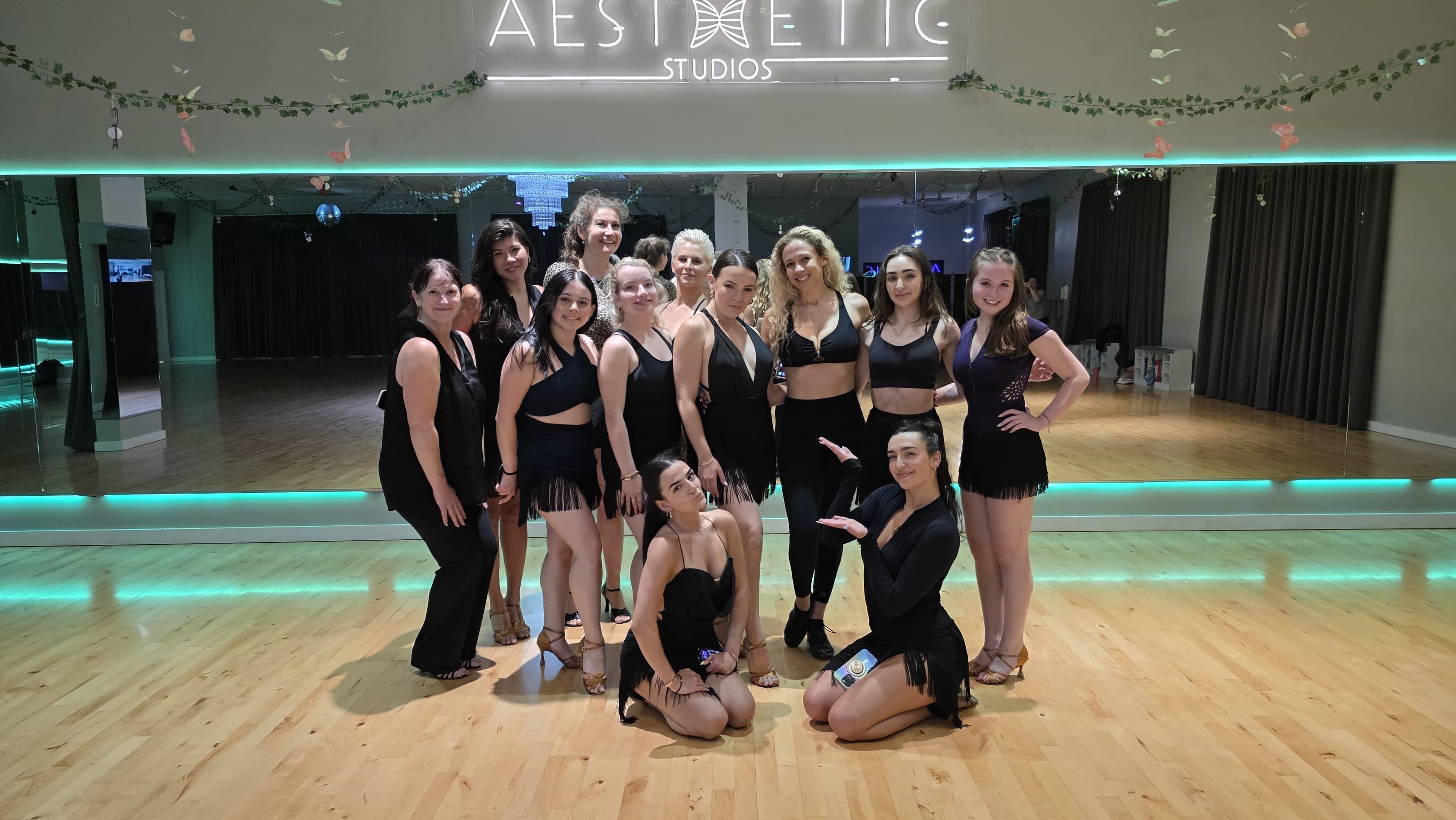 Latin class group photo in front of the Aesthetic Studios neon sign